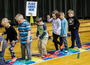 students on a hopscotch by 3s mat